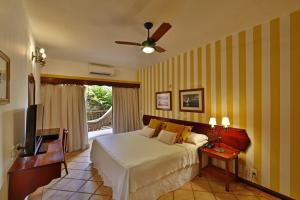 1 dormitorio con 1 cama y TV en Manary Praia Hotel, en Natal