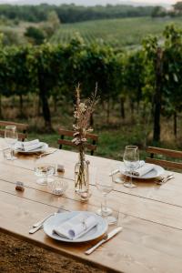 Perelli Winery في Bucine: طاولة خشبية بها صحون واكواب و مزهرية بها ورد