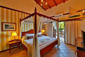 een slaapkamer met een hemelbed en een televisie bij Manary Praia Hotel in Natal