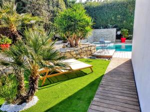 un jardín con palmeras y una piscina en La Villa Blanche, en Sanary-sur-Mer