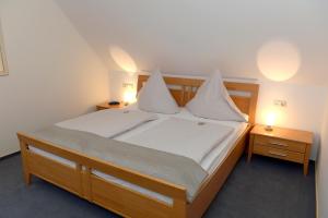 - une chambre dotée d'un grand lit avec des draps et des oreillers blancs dans l'établissement Wein und Gästehaus Scheid, à Sankt Aldegund