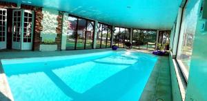 - une piscine d'eau bleue dans un bâtiment dans l'établissement Détente à la compagne piscine chauffée billard et baby foot, à Caugé