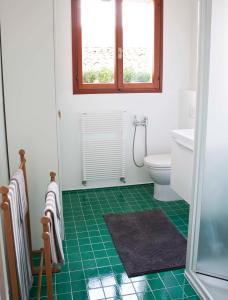 bagno con servizi igienici e pavimento piastrellato verde. di B&B ViaCavourSei a Portogruaro