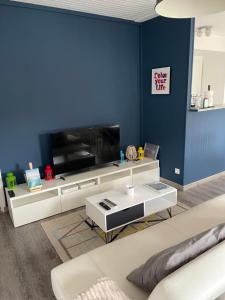 a living room with a tv and a blue wall at Villa Proche Mer St Martin de BREHAL in Bréhal