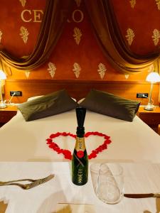 a bottle of wine sitting on a bed with a heart at Villa Riviera Hotel Udine in Pradamano