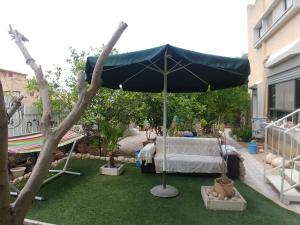 a large black umbrella in a yard with a bed at Carmela Studio in Arad