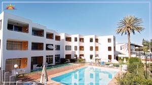a hotel with a swimming pool in front of a building at Dunas Apartment in Playa del Ingles
