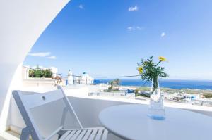 a white table and a vase with flowers on a balcony at Villa Erofili in Fira
