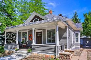 une maison blanche avec une terrasse couverte dotée d'une couronne. dans l'établissement Contemporary Sheridan Home with Porch - Walk Downtown, à Sheridan