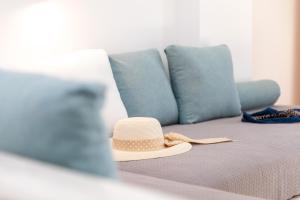 Sombrero de paja sentado en una cama con almohadas azules en Depis Place and Apartments en Naxos