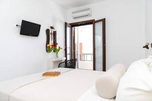 a white bedroom with a white bed and a tv at Depis Place and Apartments in Naxos Chora