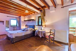 a bedroom with a bed and a table and chairs at Auberge de la Hulotte in Saint-Jacques-dʼAmbur