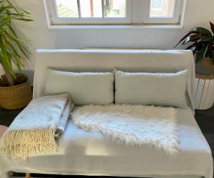 - un canapé blanc avec des oreillers et une couverture chauffante dans l'établissement Ferienwohnung Brötzingen Westliche KF - DG, à Pforzheim