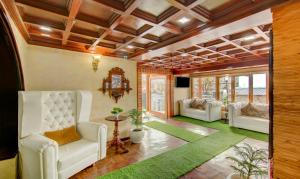 a living room with white chairs and a green rug at The Alpine Villa Mcleodganj in McLeod Ganj