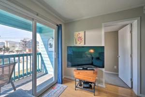 a living room with a flat screen tv and a balcony at Condo with Balcony and Pool Walk to 2 Beach Accesses! in Carolina Beach