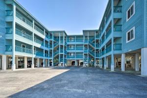 an empty parking lot in front of a blue apartment building at Condo with Balcony and Pool Walk to 2 Beach Accesses! in Carolina Beach