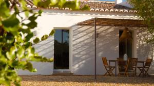 een wit huis met een tafel en stoelen bij Quinta da Pintassilga in Tavira