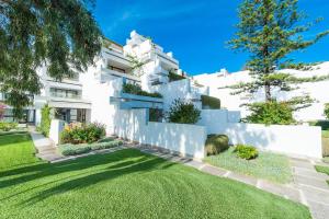 a white house with a grass yard at Apartment Oiza Classic, at Alcudia Beach in Port d'Alcudia