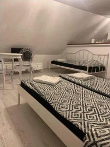 two beds in a room with a table and a beduteneway at White Apartment in Elblag