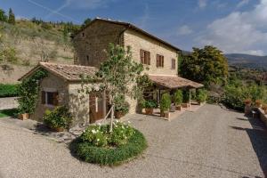 an old stone house with a tree in a driveway at Villa Tegognano in Cortona