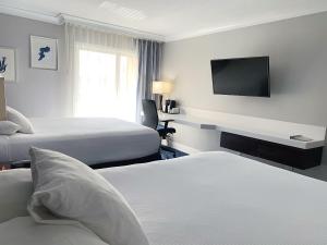 ein Hotelzimmer mit 2 Betten und einem Flachbild-TV in der Unterkunft The Pacific Inn in Seal Beach