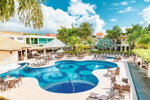 a pool at the resort with chairs and tables at Vitoria Regia Praia Hotel in Porto Seguro