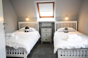 um quarto com 2 camas com lençóis brancos e uma janela em 5 Glenconon Bed and Breakfast em Uig