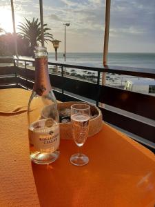 a bottle of champagne sitting on a table with a glass at Bikini Beach Holiday Home, On the Beach, Sleeps 9! in Gordonʼs Bay