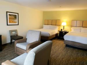 una habitación de hotel con 2 camas y una silla en Candlewood Suites Belle Vernon, an IHG Hotel, en Belle Vernon