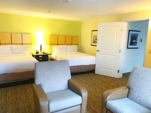 une chambre d'hôtel avec deux lits et une chaise dans l'établissement Candlewood Suites Belle Vernon, an IHG Hotel, à Belle Vernon