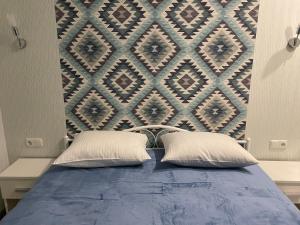 a bed with two pillows in front of a wall at Apartment Riviera in Fontanka +64 photos