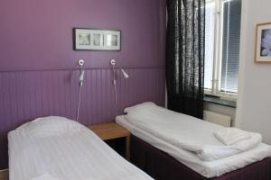 two beds in a room with purple walls at Hotel Tre Stockar in Gävle