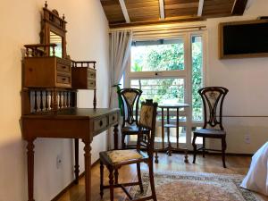 a room with a desk and chairs and a table at Pousada Pataca de prata - Pousada de Época in Petrópolis