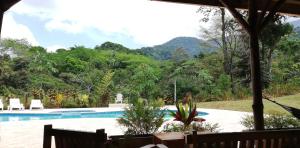 un complexe avec une piscine et des montagnes en arrière-plan dans l'établissement Hacienda Mil Bellezas - Private 40ha Jungle Reserve, à Quepos