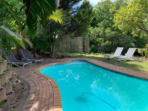 a swimming pool with two lounge chairs next to it at Private room in Ambiente Guest House in Knysna