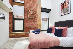 two beds in a room with a brick wall at The Grand Manhattan Apartment in Central Leeds in Leeds