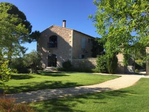 ein altes Steinhaus mit grünem Rasen in der Unterkunft Lodge Montagnac in Montagnac