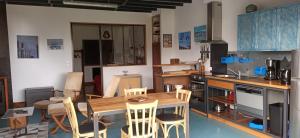 uma cozinha com uma mesa de madeira e cadeiras em LA MENUISERIE D'ANDRE em Gueures