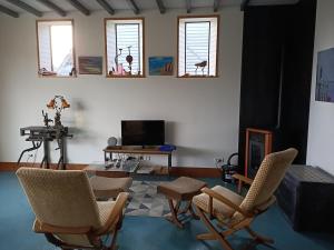 uma sala de estar com cadeiras, uma mesa e janelas em LA MENUISERIE D'ANDRE em Gueures