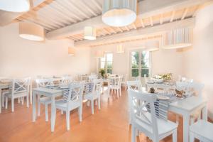een eetkamer met witte tafels en witte stoelen bij B&B Borgo di Pratavecchie in Migliarino