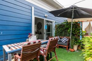 a blue house with a table and chairs and an umbrella at Sydney Executive Garden Apartments in Engadine