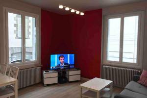 ein Wohnzimmer mit einem TV in einer roten Wand in der Unterkunft RARE PETIT COCON F1 Calme possibilité jacuzzi hammam en sus in Chamalières