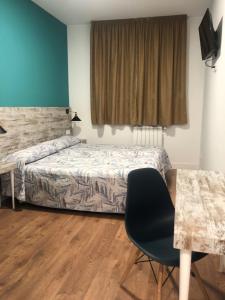 a bedroom with a bed and a desk and a chair at RoomConcept Hostel in Santo Domingo de la Calzada
