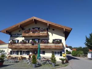 a building with a balcony with tables and chairs at Mesnerwirt in Neukirchen am Teisenberg