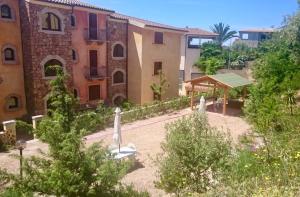 vistas a un edificio con un patio con árboles en Borgo Bellavista Badesi, en Badesi