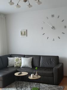 a living room with a black couch and a clock on the wall at Pomaranczowa Apartment in Szczecin