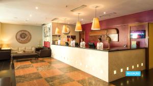 a lobby of a hotel with two women standing at a counter at Vila Galé Salvador in Salvador