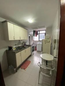 una cucina con armadi bianchi e un tavolo di Recreio, a praia mais charmosa do RJ! a Rio de Janeiro