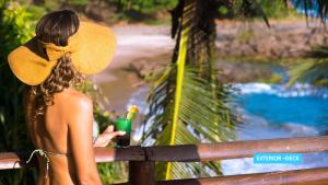 a woman in a hat sitting on a fence with a drink at Vila Galé Salvador in Salvador
