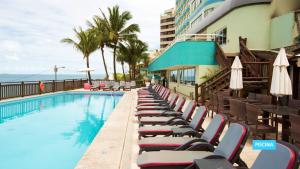 a swimming pool with lounge chairs next to a building at Vila Galé Salvador in Salvador